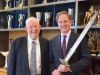 Charles Clarke and Dean Jack Knott pose with the Conan movie sword while attending a conversation hosted by the Schwarzenegger Institute.
