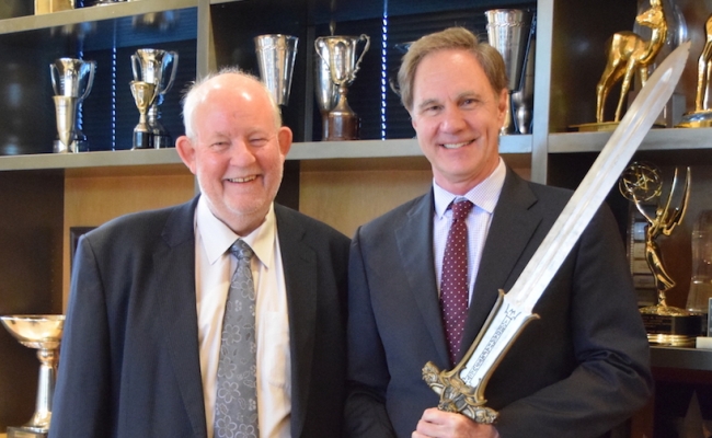 Charles Clarke and Dean Jack Knott pose with the Conan movie sword while attending a conversation hosted by the Schwarzenegger Institute.